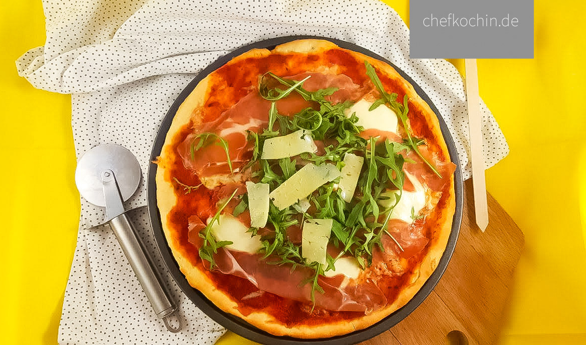 Pizza mit Rucola, Parmesan und Parmaschinken